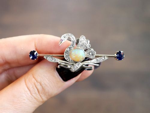fig 2. An antique Victorian 9ct gold bar brooch featuring a central swan motif set with diamonds and an oval opal body, flanked by two blue sapphires.