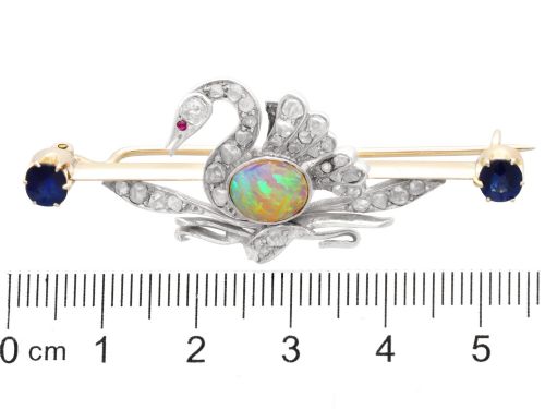 fig 8. An antique Victorian 9ct gold bar brooch featuring a central swan motif set with diamonds and an oval opal body, flanked by two blue sapphires.
