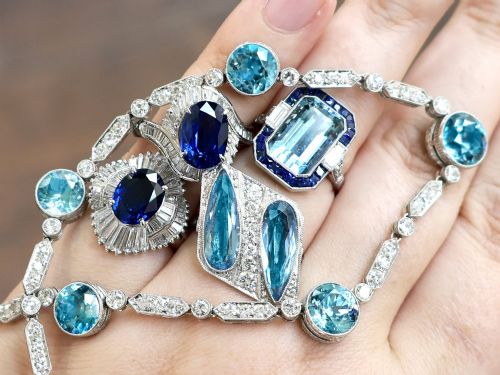 fig 4. An Art Deco platinum cocktail ring featuring two pear-cut light blue aquamarines set diagonally beside a central row of round diamonds with millegrain borders.