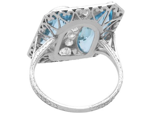 fig 6. An Art Deco platinum cocktail ring featuring two pear-cut light blue aquamarines set diagonally beside a central row of round diamonds with millegrain borders.