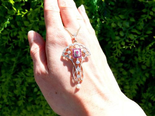 fig 1. An Edwardian openwork yellow gold pendant set with a central square-cut ruby surrounded by small rubies, diamonds, and a suspended natural pearl drop.