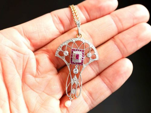 fig 2. An Edwardian openwork yellow gold pendant set with a central square-cut ruby surrounded by small rubies, diamonds, and a suspended natural pearl drop.