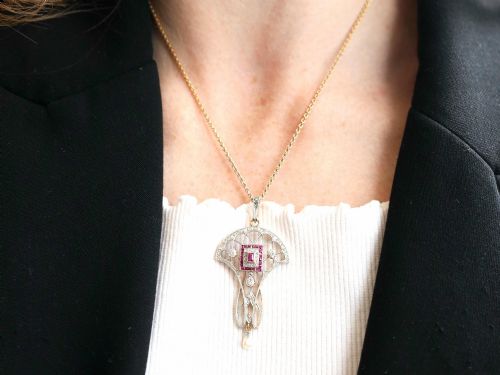 fig 3. An Edwardian openwork yellow gold pendant set with a central square-cut ruby surrounded by small rubies, diamonds, and a suspended natural pearl drop.