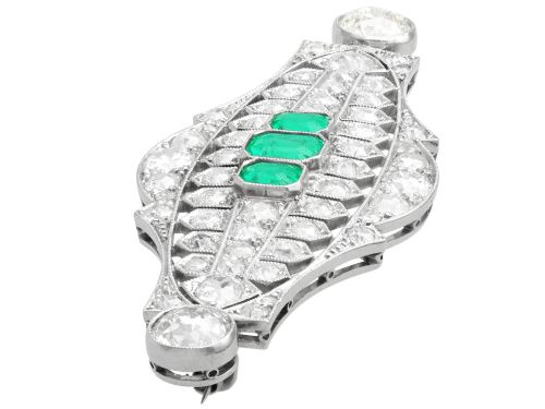 fig 4. An Art Deco platinum brooch featuring three central step-cut green emeralds surrounded by a geometric lattice of diamonds with millegrain borders.