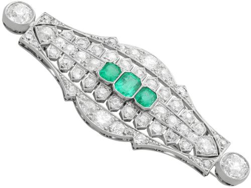 fig 5. An Art Deco platinum brooch featuring three central step-cut green emeralds surrounded by a geometric lattice of diamonds with millegrain borders.
