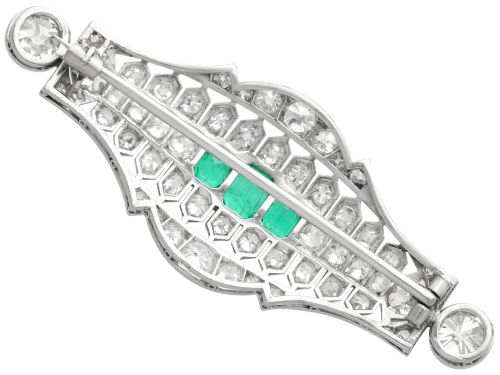 fig 6. An Art Deco platinum brooch featuring three central step-cut green emeralds surrounded by a geometric lattice of diamonds with millegrain borders.