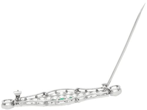 fig 7. An Art Deco platinum brooch featuring three central step-cut green emeralds surrounded by a geometric lattice of diamonds with millegrain borders.