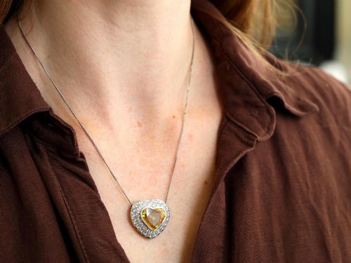 fig 2. A platinum heart-shaped pendant set with a central faceted yellow sapphire surrounded by a double border of round diamonds.