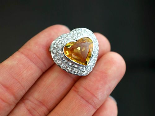 fig 5. A platinum heart-shaped pendant set with a central faceted yellow sapphire surrounded by a double border of round diamonds.