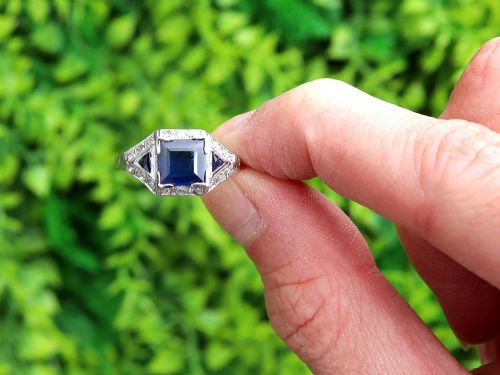 fig 1. An Art Deco platinum ring featuring a central rectangular step-cut blue sapphire flanked by triangular sapphires and diamond-set shoulder details.