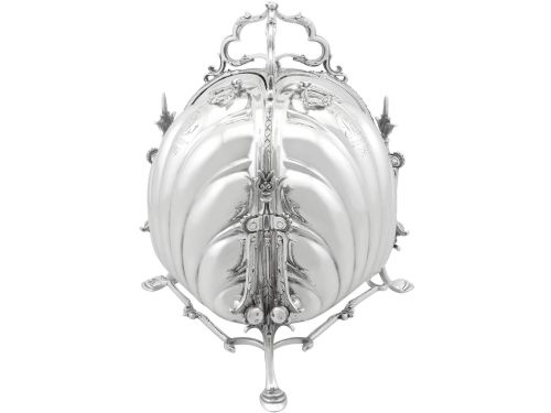 fig 1. An antique Victorian sterling silver folding biscuit box featuring shell-form compartments, an ornate looped handle, and an engraved 1897 monogram.
