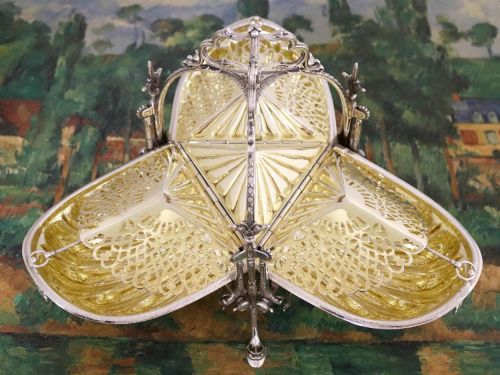 fig 4. An antique Victorian sterling silver folding biscuit box featuring shell-form compartments, an ornate looped handle, and an engraved 1897 monogram.