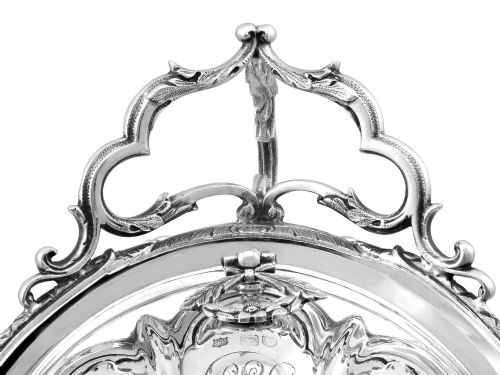 fig 8. An antique Victorian sterling silver folding biscuit box featuring shell-form compartments, an ornate looped handle, and an engraved 1897 monogram.