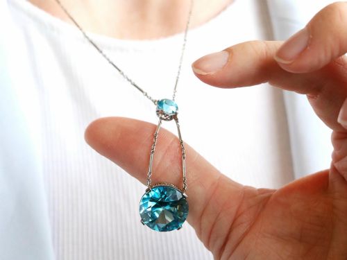 fig 4. An Art Deco 18ct white gold drop pendant set with two round brilliant-cut bright blue zircon gemstones suspended on delicate bar links.