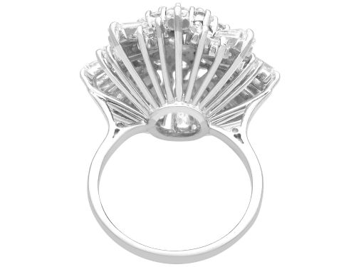 fig 8. A vintage 18ct white gold cluster ring featuring a central round brilliant cut diamond surrounded by a halo of brilliant cut diamonds and an outer sunburst tier of tapered baguette diamonds.