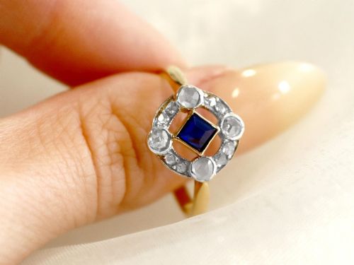 fig 2. An 18ct yellow gold ring featuring a central square blue sapphire surrounded by an openwork diamond-set frame.