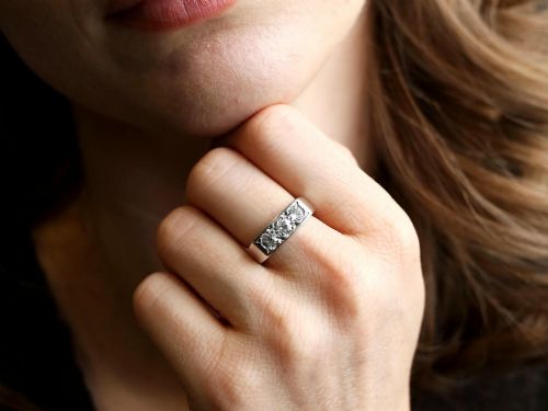 fig 2. An 18ct white gold Art Deco trilogy ring featuring three round diamonds set horizontally across a wide band.