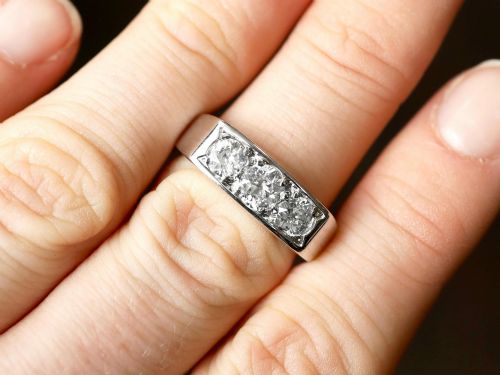 fig 3. An 18ct white gold Art Deco trilogy ring featuring three round diamonds set horizontally across a wide band.