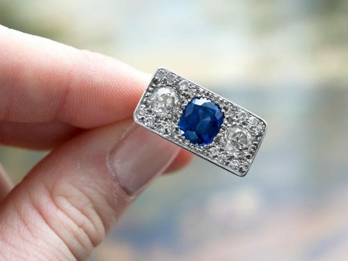 fig 1. An Art Deco platinum plaque ring set with a central blue sapphire flanked by two large diamonds and surrounded by smaller pave-set diamonds.
