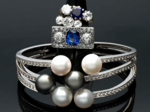 fig 5. An Art Deco platinum plaque ring set with a central blue sapphire flanked by two large diamonds and surrounded by smaller pave-set diamonds.
