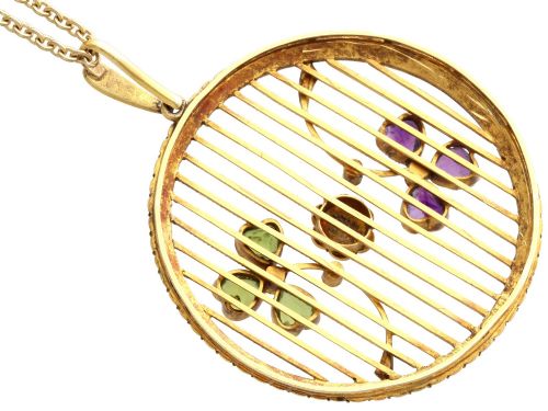 fig 9. A circular 18ct yellow gold openwork pendant set with seed pearls along the outer rim, containing peridot and amethyst trefoil motifs and a central seed pearl cluster.
