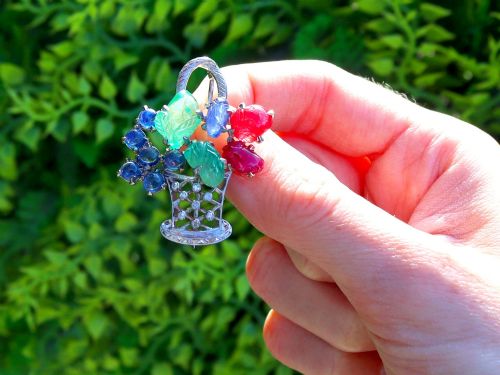 fig 1. An 18ct white gold Tutti Frutti basket brooch featuring carved emeralds, rubies, sapphire cabochons, and small diamonds.