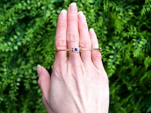 fig 1. An antique 15ct yellow gold hinged bangle featuring a central circular cluster of diamonds around a dark blue sapphire.