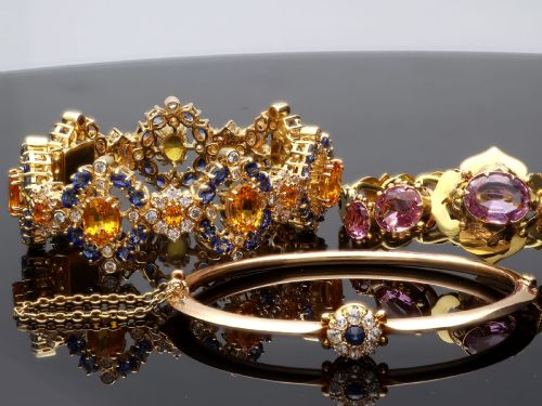 fig 4. An antique 15ct yellow gold hinged bangle featuring a central circular cluster of diamonds around a dark blue sapphire.