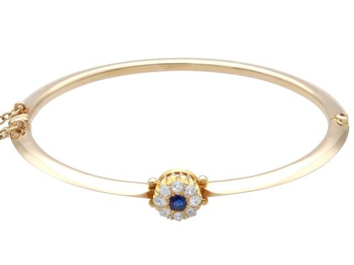 fig 6. An antique 15ct yellow gold hinged bangle featuring a central circular cluster of diamonds around a dark blue sapphire.