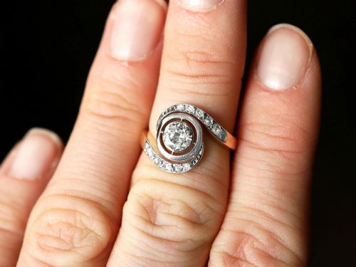 fig 3. An antique 18ct yellow gold twist ring featuring a central round diamond set within a swooping platinum accent band set with smaller diamonds.