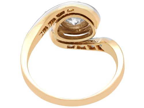 fig 8. An antique 18ct yellow gold twist ring featuring a central round diamond set within a swooping platinum accent band set with smaller diamonds.