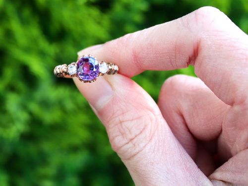 fig 1. A Victorian 15ct rose gold trilogy ring set with a central purple sapphire flanked by two diamonds on carved shoulders.