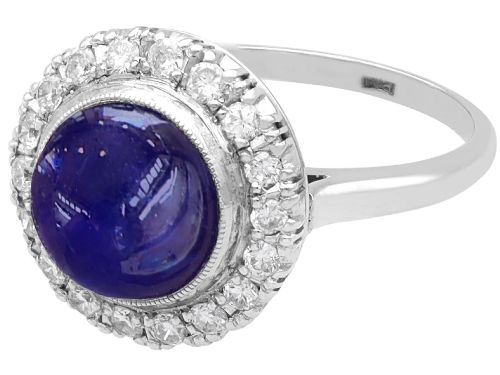 fig 5. An Art Deco platinum cluster ring featuring a central cabochon star sapphire encircled by a halo of round diamonds with millegrain edging.