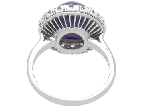 fig 6. An Art Deco platinum cluster ring featuring a central cabochon star sapphire encircled by a halo of round diamonds with millegrain edging.