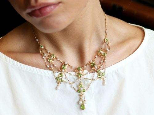 fig 4. An 18ct yellow gold Belle Epoque festoon necklace featuring faceted green peridots, intricate scrollwork, and suspended natural pearl drops.