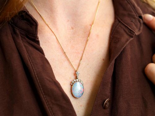 fig 4. An Edwardian 9ct yellow gold pendant featuring an oval cabochon opal surmounted by millegrain-set diamonds.