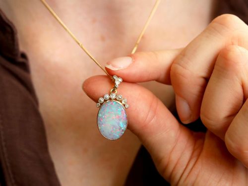 fig 5. An Edwardian 9ct yellow gold pendant featuring an oval cabochon opal surmounted by millegrain-set diamonds.