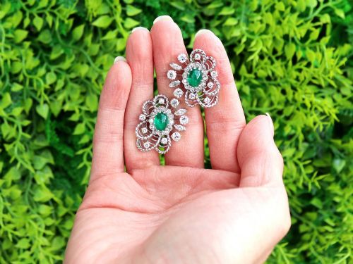 fig 1. A pair of platinum and palladium clip earrings featuring oval central emeralds surrounded by brilliant-cut diamonds and rope-twist metalwork.