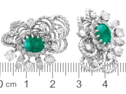 fig 8. A pair of platinum and palladium clip earrings featuring oval central emeralds surrounded by brilliant-cut diamonds and rope-twist metalwork.