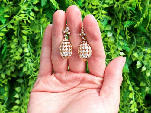 fig 1. A pair of 18ct yellow gold drop earrings featuring fleur-de-lis surmounts above openwork teardrop cages set with round diamonds.