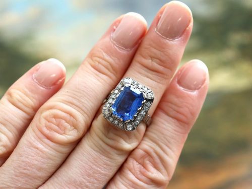 fig 1. An Art Deco 18ct white gold ring featuring a central octagonal step-cut blue Ceylon sapphire surrounded by a geometric diamond halo with milgrain details.