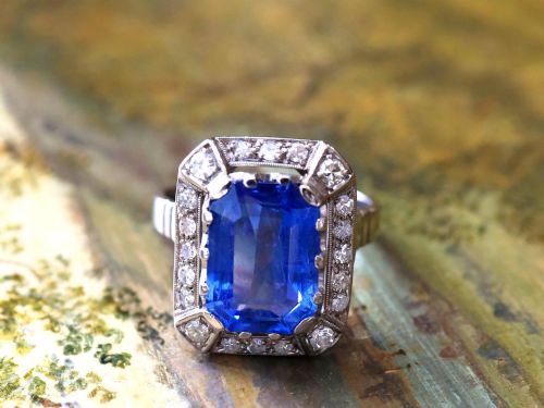fig 4. An Art Deco 18ct white gold ring featuring a central octagonal step-cut blue Ceylon sapphire surrounded by a geometric diamond halo with milgrain details.