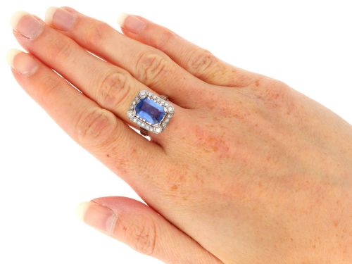 fig 8. An Art Deco 18ct white gold ring featuring a central octagonal step-cut blue Ceylon sapphire surrounded by a geometric diamond halo with milgrain details.