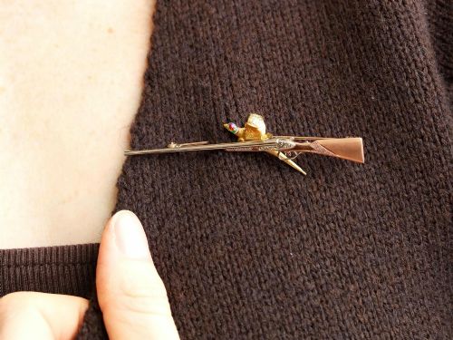 fig 4. A vintage 9ct gold brooch depicting a flying pheasant with a red and green enamelled head positioned alongside a shotgun.