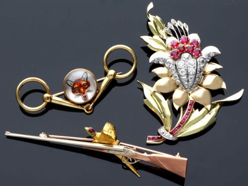 fig 5. A vintage 9ct gold brooch depicting a flying pheasant with a red and green enamelled head positioned alongside a shotgun.