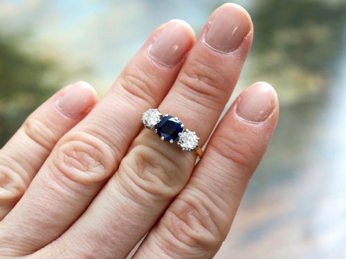 fig 2. An antique 18ct yellow gold trilogy ring featuring a cushion-shaped blue sapphire flanked by two brilliant-cut diamonds in claw settings.