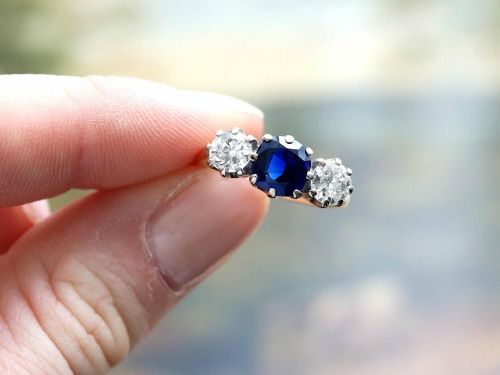 fig 3. An antique 18ct yellow gold trilogy ring featuring a cushion-shaped blue sapphire flanked by two brilliant-cut diamonds in claw settings.
