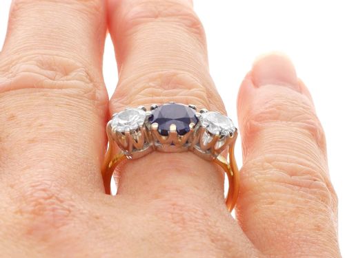 fig 10. An antique 18ct yellow gold trilogy ring featuring a cushion-shaped blue sapphire flanked by two brilliant-cut diamonds in claw settings.