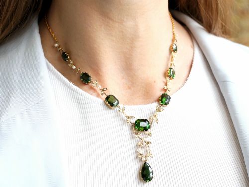 fig 2. A late Victorian 14ct yellow gold necklace featuring emerald-cut green tourmalines connected by seed pearl foliate links and terminating in a pear-cut green tourmaline drop pendant.