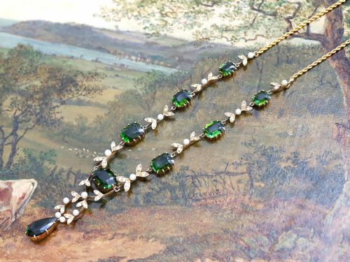 fig 6. A late Victorian 14ct yellow gold necklace featuring emerald-cut green tourmalines connected by seed pearl foliate links and terminating in a pear-cut green tourmaline drop pendant.